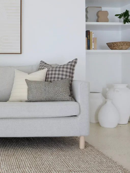 A set of 5 designer sofa cushions are arranged nicely on a light grey sofa in a living room.