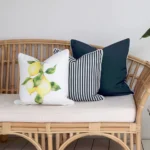Outdoor seating with a set of three outdoor couch cushions, including one lemon-printed, one solid navy-coloured, and one striped navy-coloured on a seat.