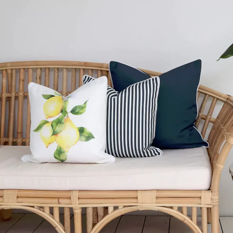Outdoor seating with a set of three outdoor couch cushions, including one lemon-printed, one solid navy-coloured, and one striped navy-coloured on a seat.