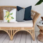 3 navy-coloured outdoor couch cushions are neatly arranged in a corner of a rattan seat.