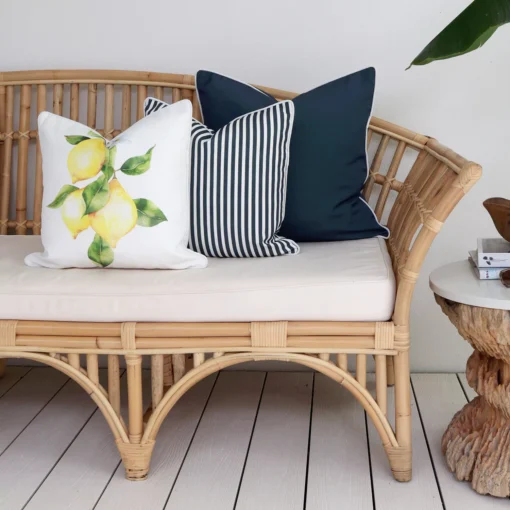 3 navy-coloured outdoor couch cushions are neatly arranged in a corner of a rattan seat.