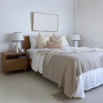 4 designer cushions placed perfectly on a wooden bed between two bedside tables.