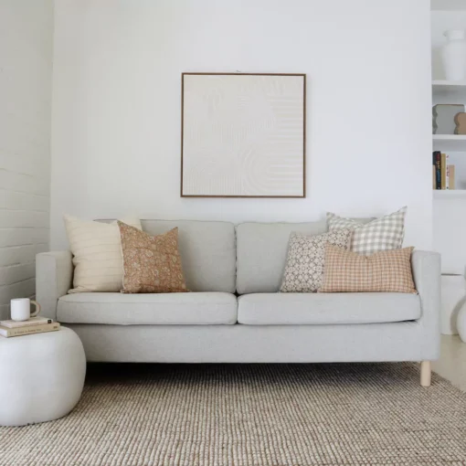 A beautiful combination of 5 designer cushions positioned on light grey sofa.
