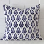 A brick wall that has a geometric blue cushion cover positioned in front of it. It has an exquisite linen material and a lovely large size.