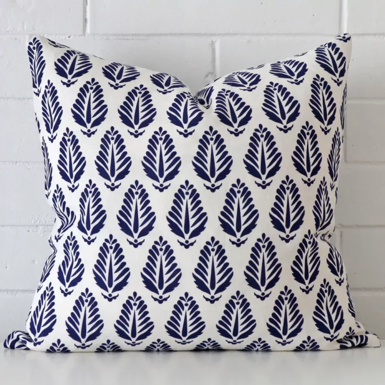 A brick wall that has a geometric blue cushion cover positioned in front of it. It has an exquisite linen material and a lovely large size.