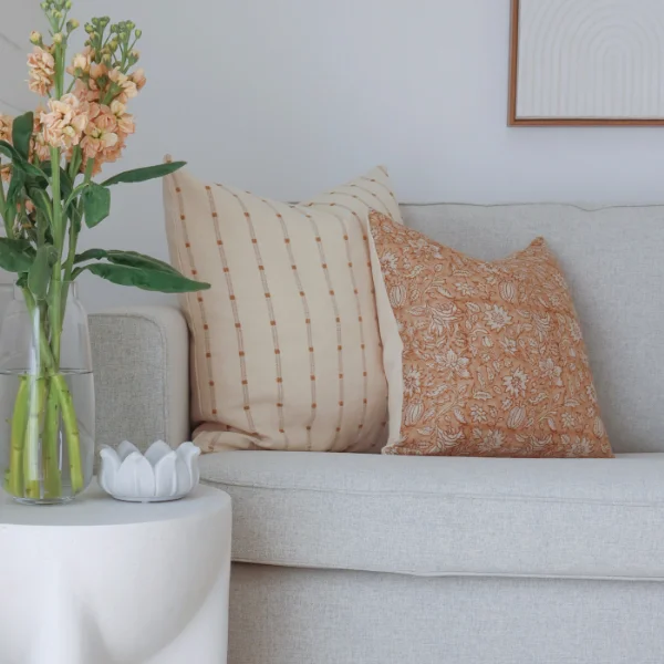 A living room is shown with lounge cushions on display next to a side table.
