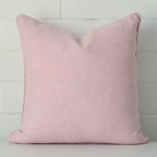 A bold linen cushion in a sleek square size with a baby pink tone of colour.