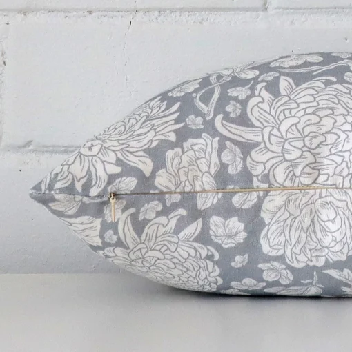 Horizontal edge view of front and back panels of a floral linen cushion in a rectangle size and with light blue colouring.