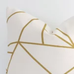 A geometric cushion with a gold mustard print positioned on its back panel. The shot shows a lateral view of the linen fabric and its square shape.