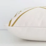 A square cushion with a gold mustard print cover laying flat. This viewpoint highlights the geometric style and linen fabric.