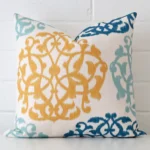 A brick wall that has a patterned cushion cover positioned in front of it. It has an exquisite linen material and a lovely square shape.