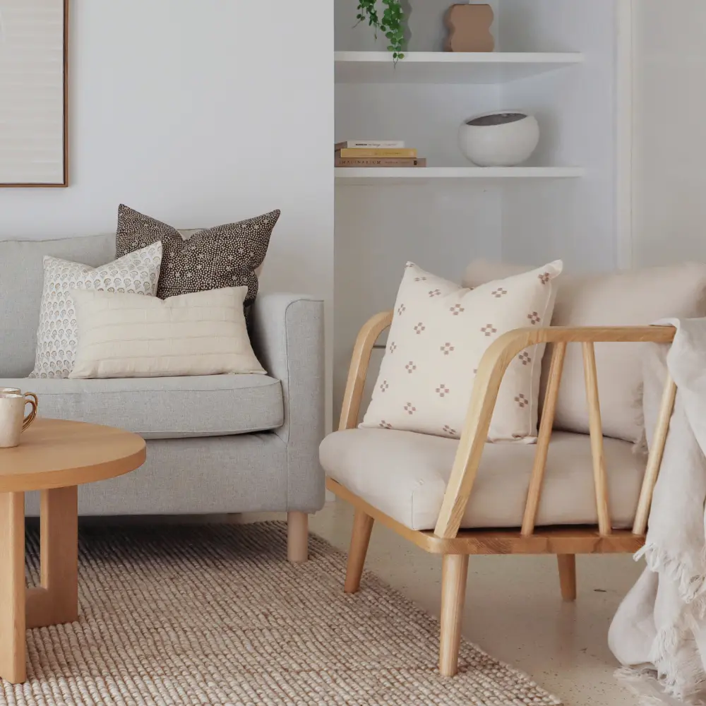 A modern living room is shown with a couch and chair styled with indoor cushions.