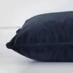 Rectangle cushion in navy colour laying flat. The viewpoint highlights the seams of the velvet fabric.