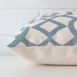 Lateral angle image of a linen square cushion. The patterned design is highlighted along its seams.