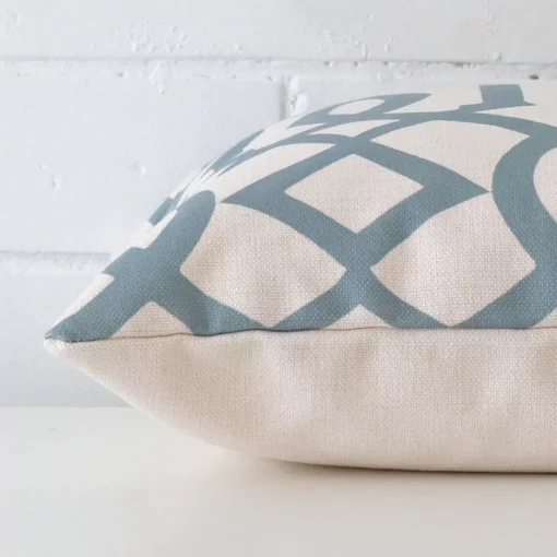Lateral angle image of a linen square cushion. The patterned design is highlighted along its seams.
