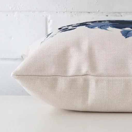 Horizontal edge of floral square cushion cover is shown. The linen fabric can be seen from this side view.