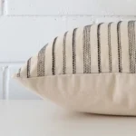 Lateral angle image of a designer cushion. The striped design is highlighted along its seams.