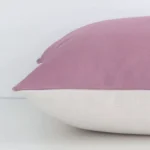 Horizontal edge of solid colour square cushion cover is shown. The linen fabric and blush tone can be seen from this side view.