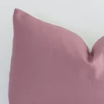 Extreme close up of a rectangle blush cushion. The solid colour style and linen fabric are shown with a much higher degree of detail.