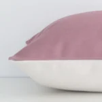 The seams of this linen rectangle cushion cover in blush are shown. The image shows the solid colour design and how the panels are attached.