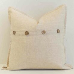 Oatmeal linen cushion with button closure detail and natural woven texture.