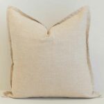Oatmeal linen cushion with button closure detail and natural woven texture.