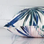 Enlarged image of the side of this pink outdoor cushion. The angle highlights how the square design and decorative finish are joined along the seam.