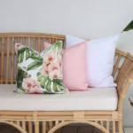 A set of three pink coloured outdoor cushions arranged beautifully on a rattan seat.