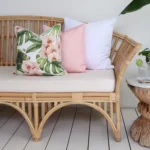 A shot capturing the corner of a rattan seat with 3 pink outdoor couch cushions.