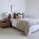 A wooden bed with 4 designer bed cushions in a bright room.