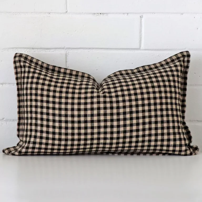 A rectangle gingham cushion in a delightful tone rests against a white wall. The designer material appears to be of exceptional quality.