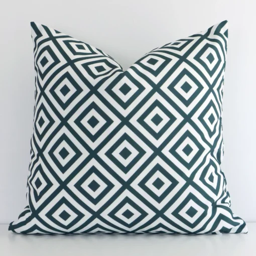 Green geometric cushion leans elegantly against a white wall. It has been crafted from a high quality outdoor material and has a square shape.