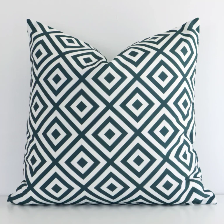 Green geometric cushion leans elegantly against a white wall. It has been crafted from a high quality outdoor material and has a square shape.