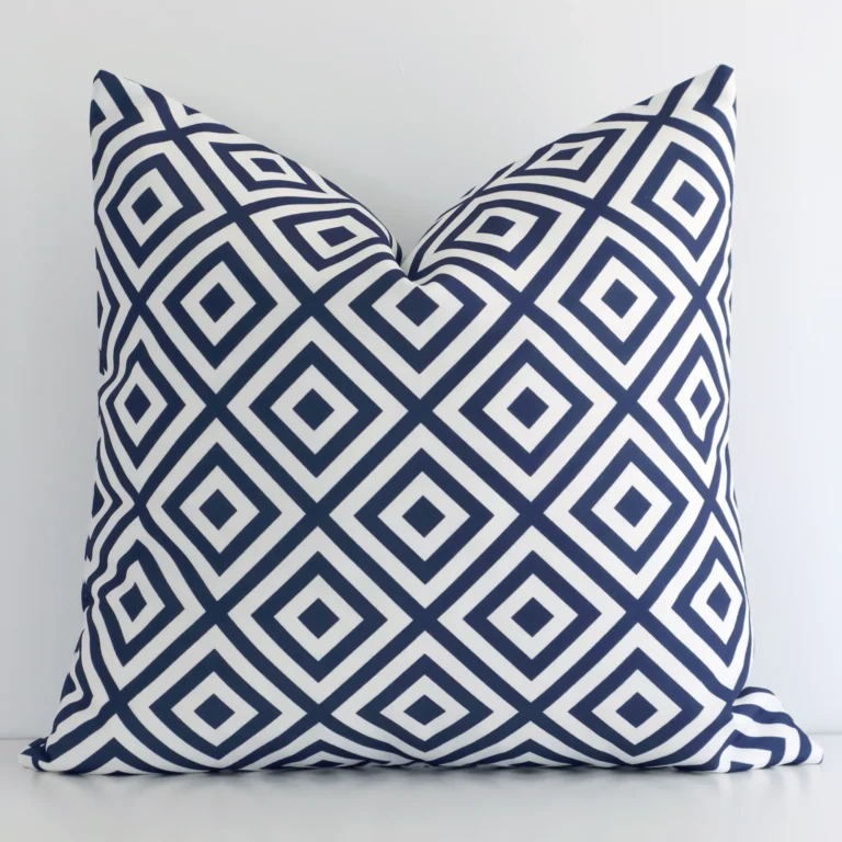 An attractive geometric outdoor cushion in front of a white wall. It has a square shape and the print is navy in colour.