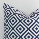 Magnified view of this outdoor cushion cover’s corner showing a navy geometric design and its square size.