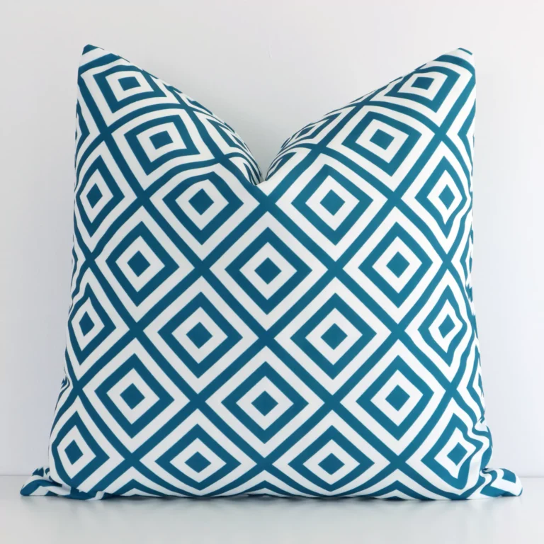 Teal outdoor cushion cover features prominently against a white wall. It is a square design and has a geometric decorative finish.