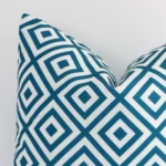 A detailed shot of this teal geometric cushion cover that has outdoor fabric and has a square size.