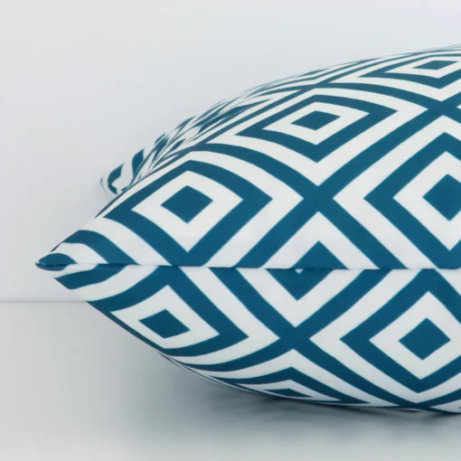 Square geometric cushion cover in teal colour sitting flat. The sideways viewpoint shows the seams of the outdoor material.