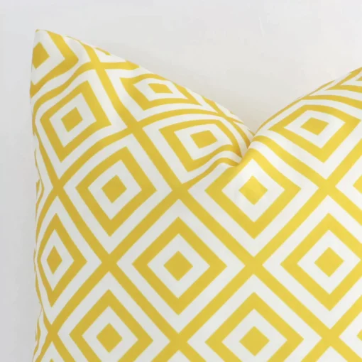 A yellow outdoor cushion cover’s corner is shown in more detail. It is possible to see the square design and geometric decorative finish in much more detail.