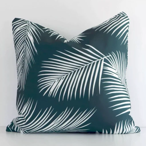 A square palm styled cushion in a delightful green tone rests against a white wall. The outdoor material appears to be of exceptional quality.