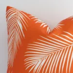 Zoomed photo of the top left corner of this orange palm printed cushion cover. The image clearly shows the outdoor material and square dimensions.