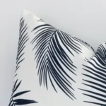 A very close image of the corner of a palm printed outdoor cushion.The finer detail of the rectangle shape and black and white colour are visible.