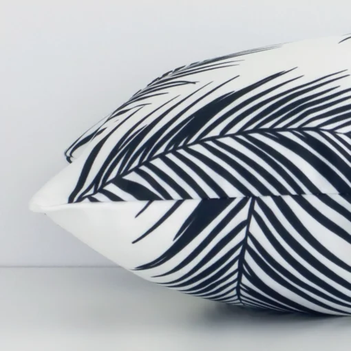 The seams of this outdoor rectangle cushion cover in black and white are shown. The image shows the palm printed design and how the panels are attached.