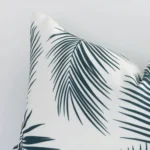 A zoomed in photo of the corner of a green palm cushion that has outdoor fabric and a rectangular size.