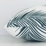 Rectangular palm designed cushion in green colour laying flat. The viewpoint highlights the seams of the outdoor fabric.