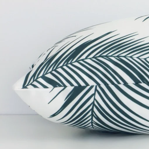 Rectangular palm designed cushion in green colour laying flat. The viewpoint highlights the seams of the outdoor fabric.
