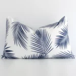 Navy palm cushion positioned in front of a brick wall. It has rectangle dimensions and is made from an outdoor material.