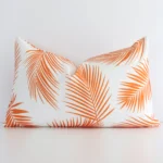 A lovely rectangle orange palm leaf printed cushion cover arranged in front of a white wall. The palm style complements the outdoor material.