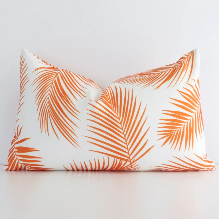 A lovely rectangle orange palm leaf printed cushion cover arranged in front of a white wall. The palm style complements the outdoor material.