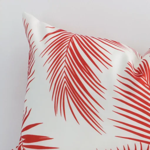 A close up shot showing the top left side of this rectangle outdoor cushion cover. The red tone and palm design are magnified.